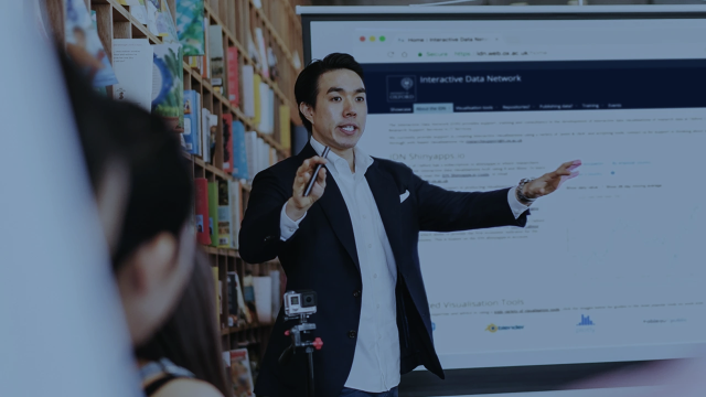 A man giving a presentation to a group in a library or college setting