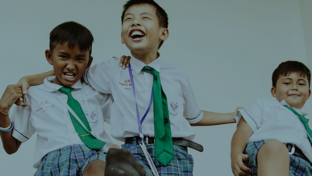 3 smiling, young boys from Thailand wearing school uniforms and playing.