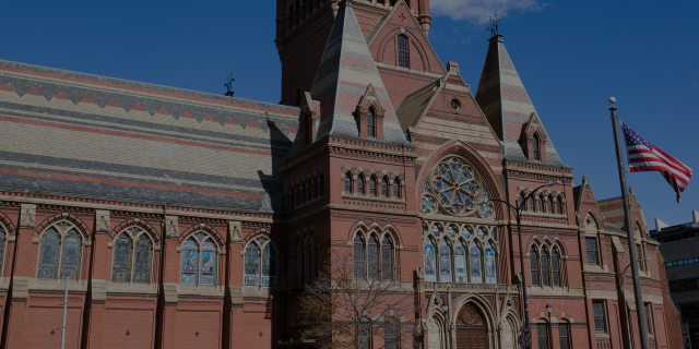 A harvard building, brick with a copper roof and a big stained glass window