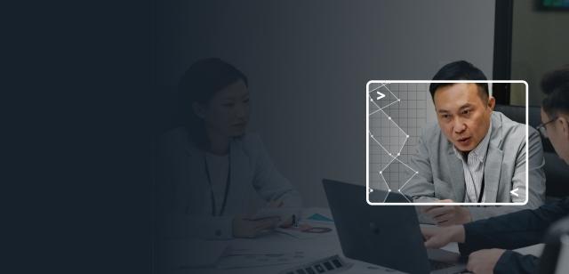 Blue-tinted background of business people with a bright inset focus on a man pointing at a laptop.