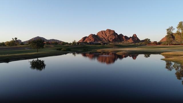 A reflective lake with red rocks and a mountain on the horizon