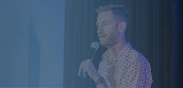 A blue-tinted image of Hadley Wickham speaking into a microphone during a presentation.