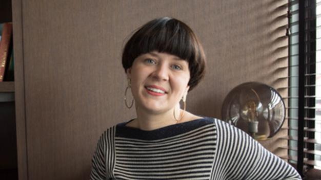 portrait of Kristi Angel smiling in an office next to window with blinds