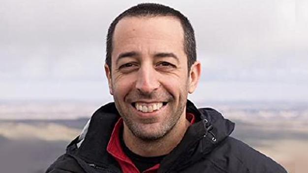 portrait of Rami Krispin outside with blurry landscape in the background