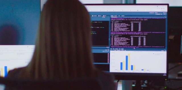 A woman working on a monitor with RStudio open