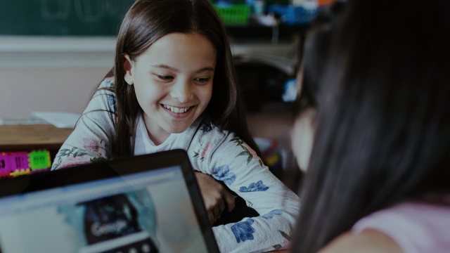 Two girls laughing and working on a slideshow