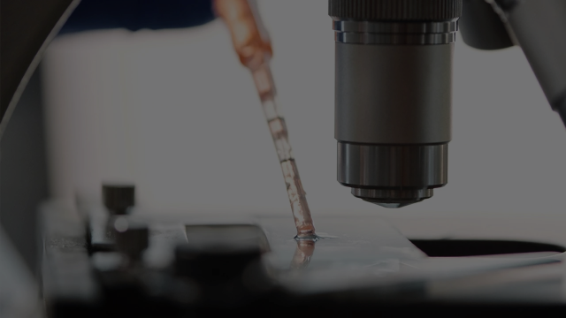 A dropper putting a sample under a microscope