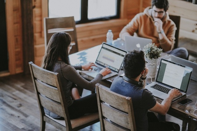 Colleagues around a table working on their laptops