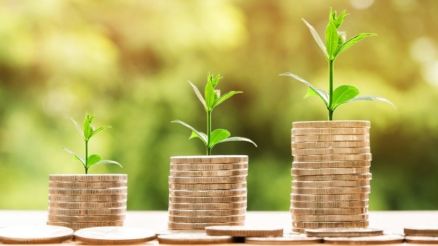 A stack of coins in increasing sizes, each with a sprout coming out of the top.