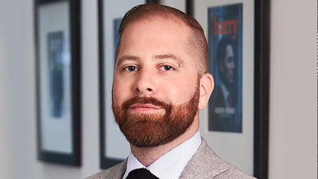 portrait of Jay Sewell in front of wall with three framed magazine covers