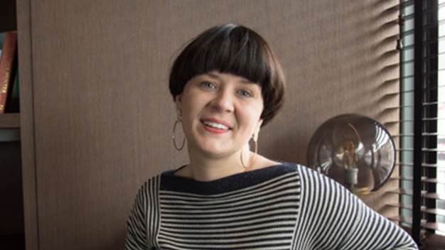 portrait of Kristi Angel smiling in an office next to window with blinds