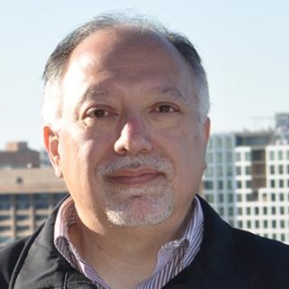 portrait of David Mexa outside with high-rise buildings in the background