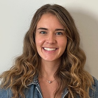 portrait of smiling Rachael Dempsey standing in front of off-white wall