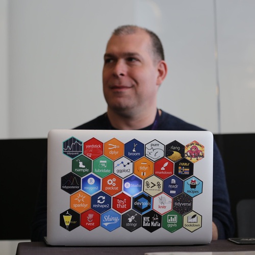 portrait of Max Kuhn sitting in front of laptop covered with hex stickers