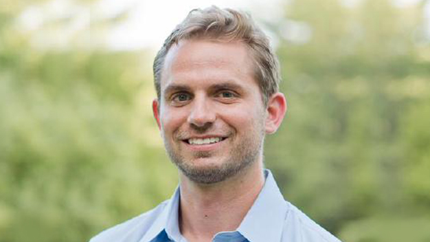 portrait of Chase Carpenter outside in front of blurry greenery in the background