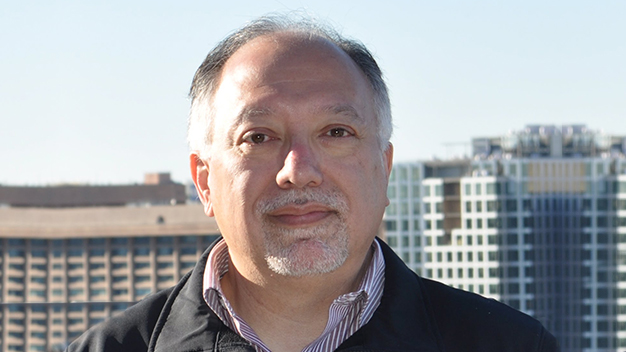 portrait of David Mexa outside with high-rise buildings in the background