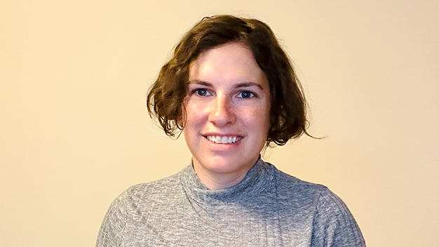 portrait of Jacqueline Nolis smiling in front of cream colored wall