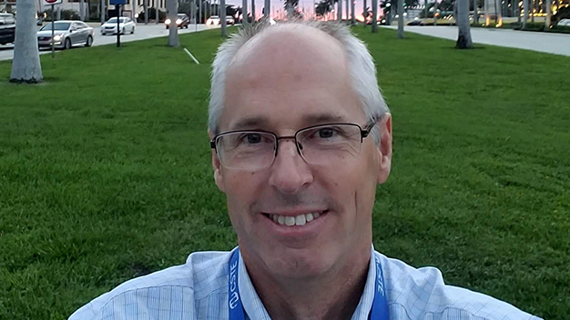 portrait of smiling Joe Gibson outside in front of large grassy area