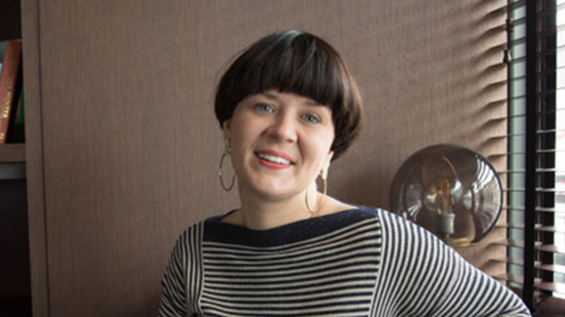 portrait of Kristi Angel smiling in an office next to window with blinds