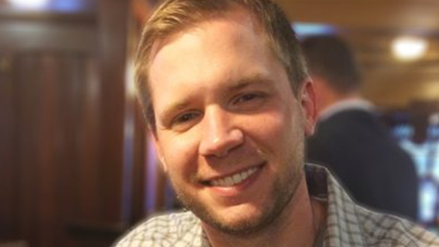 Close up photo of Matt Dancho standing in front of a wood paneled room