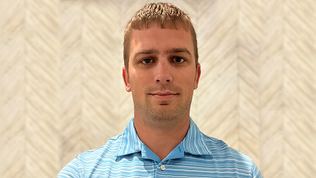 portrait of Mike Miller standing in front of wall with geometric arrow pattern