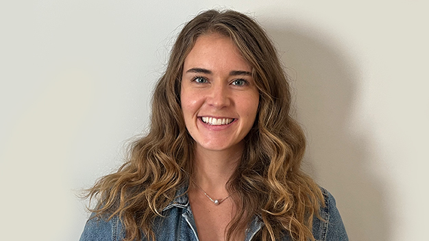 portrait of smiling Rachael Dempsey standing in front of off-white wall