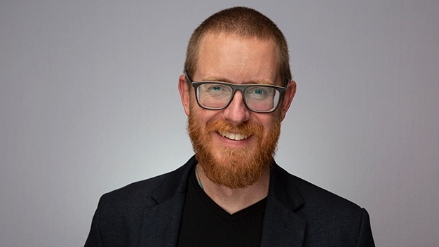 portrait of Travis Gerke in front of gray background