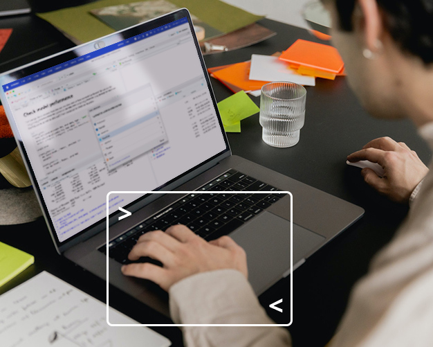 Individual sitting at a desk working on a laptop with Posit product on screen and hand framed with computer terminal graphic