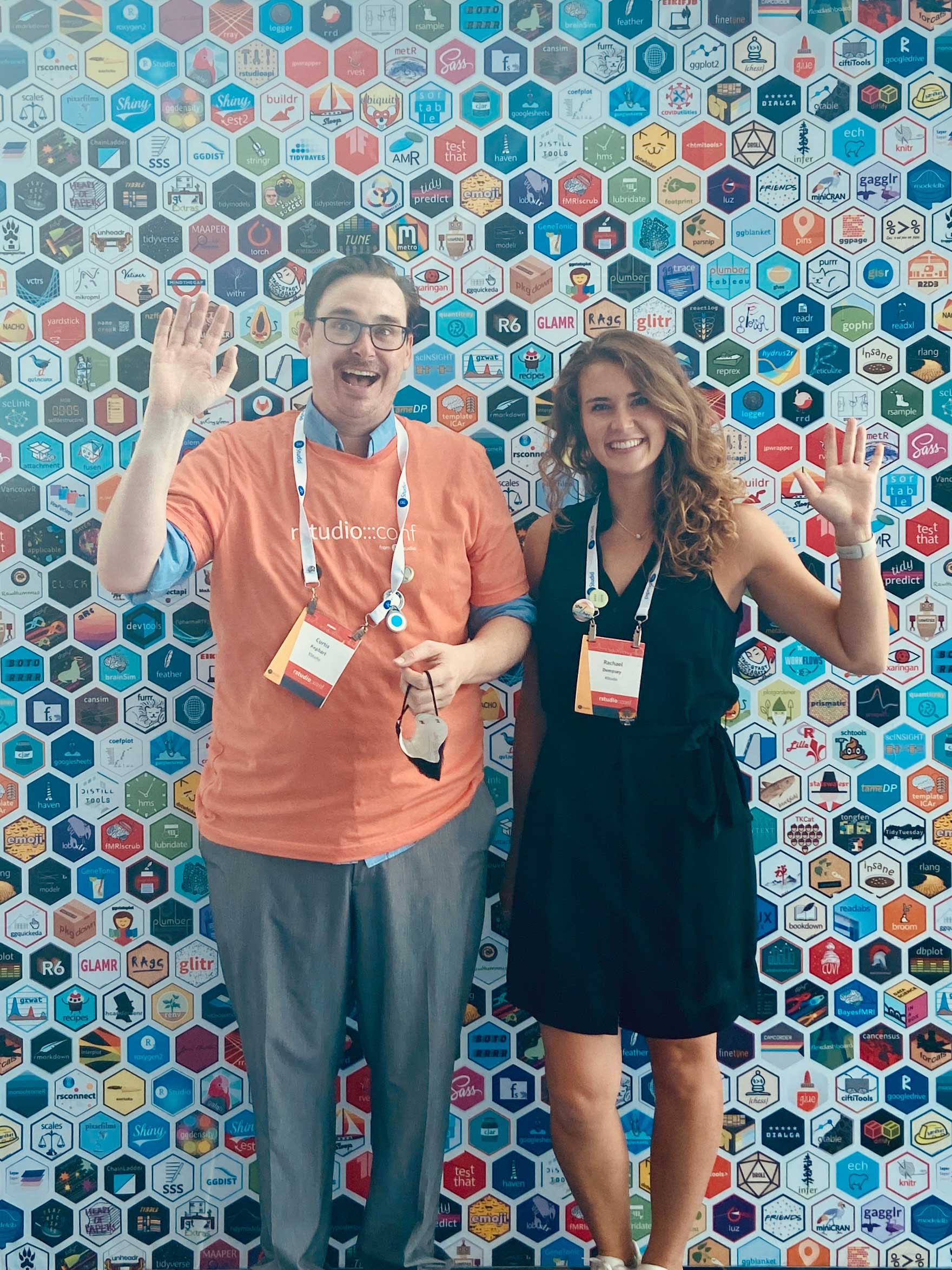 Curtis Kephart and Rachael Dempsey waving in front of hex packages wall
