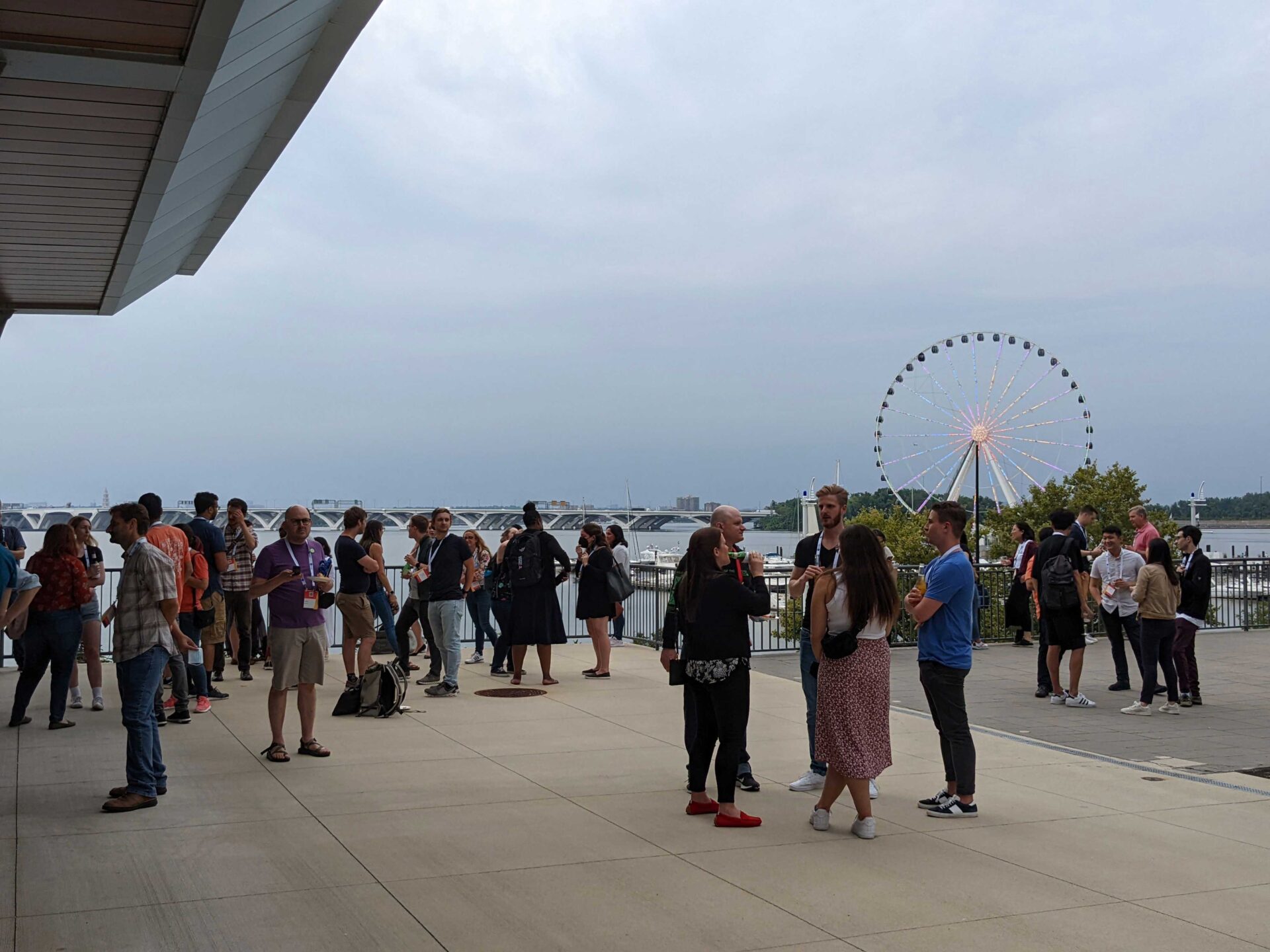people standing gathered outside in front of National Harbor ferris wheel