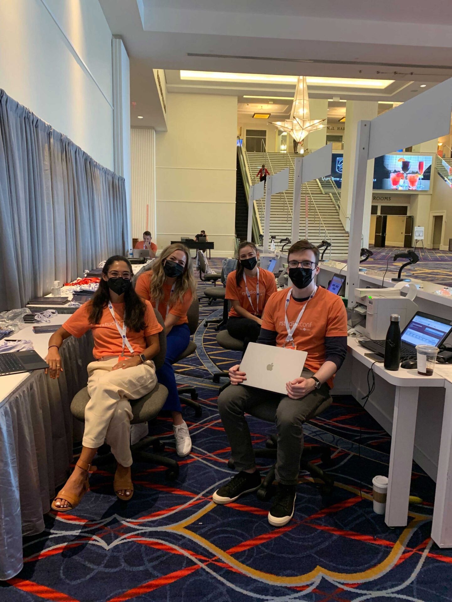 4 Posit employees in orange shirts at the registration area conf 2022
