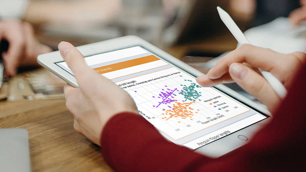 Hands of person reviewing scatterplot on a tablet