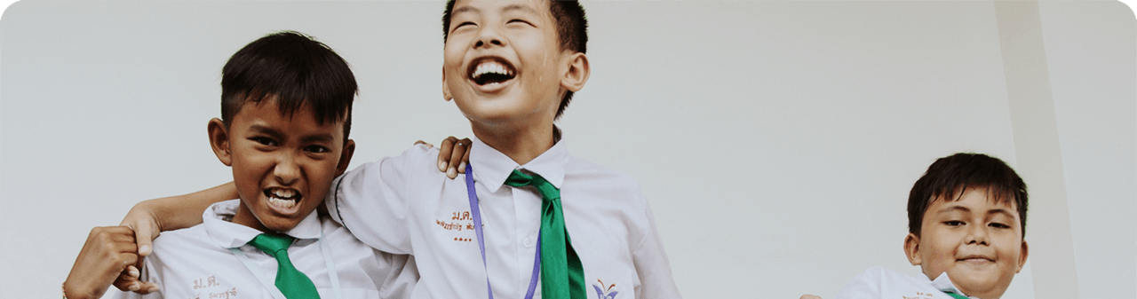 3 young, smiling boys from Thailand in school uniforms
