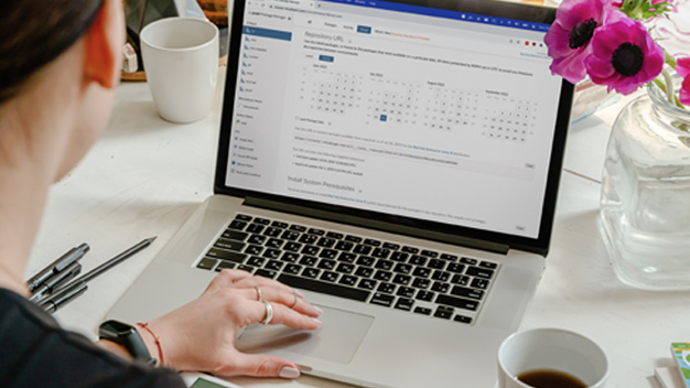 over the shoulder image of a person at a laptop with the Posit Package Manager calendar UI