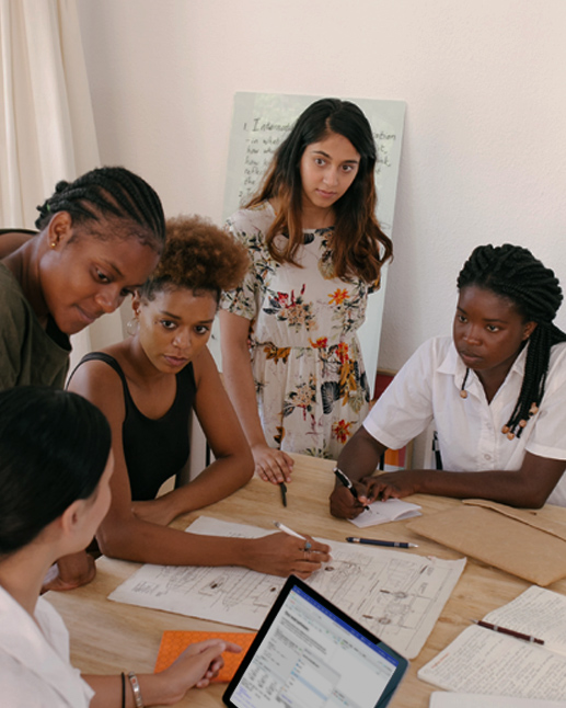 A diverse team of women working on a project sketching on paper and working on computer