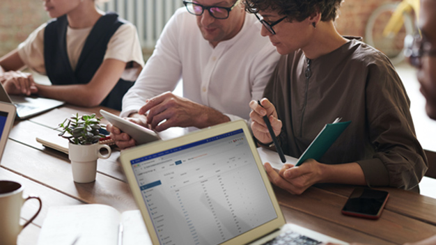 people at a table reviewing a tablet in a meeting and laptop open with Posit UI