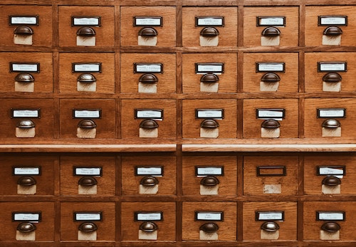 A closeup of small wooden cabinet doors with name tags and metal handles