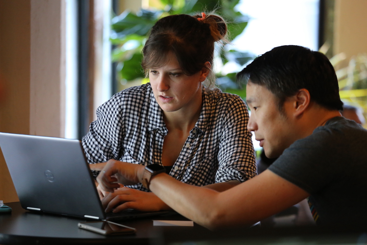 Two people looking at the screen of a laptop with one person pointing at the screen.