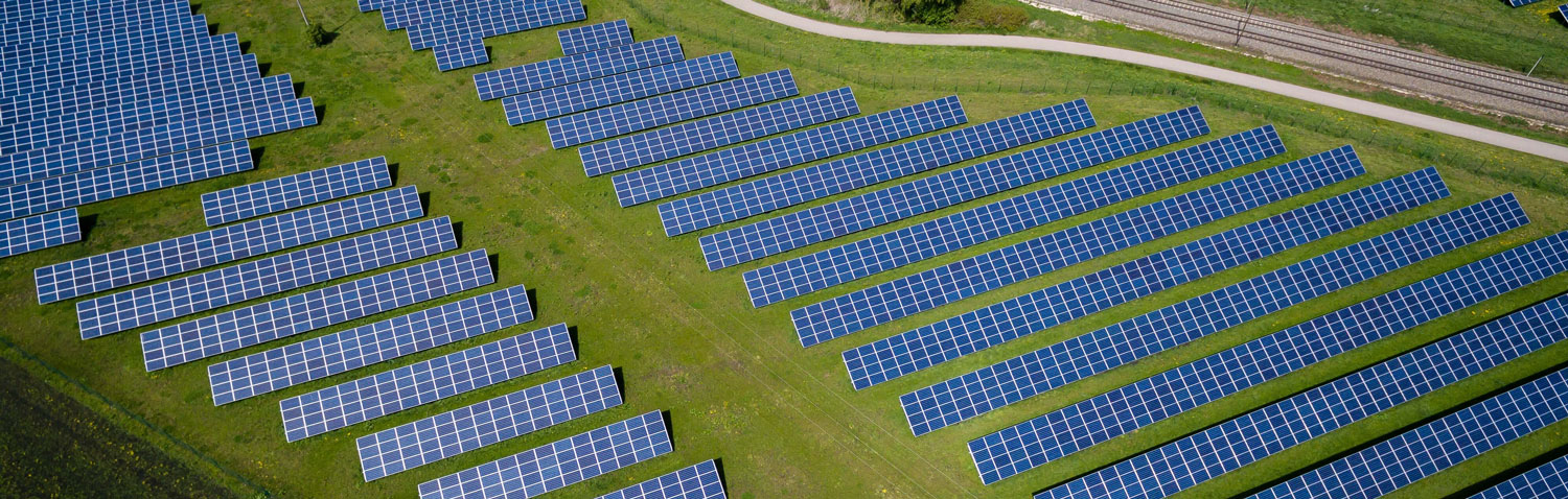 Aerial shot of solar panels lining a grass field