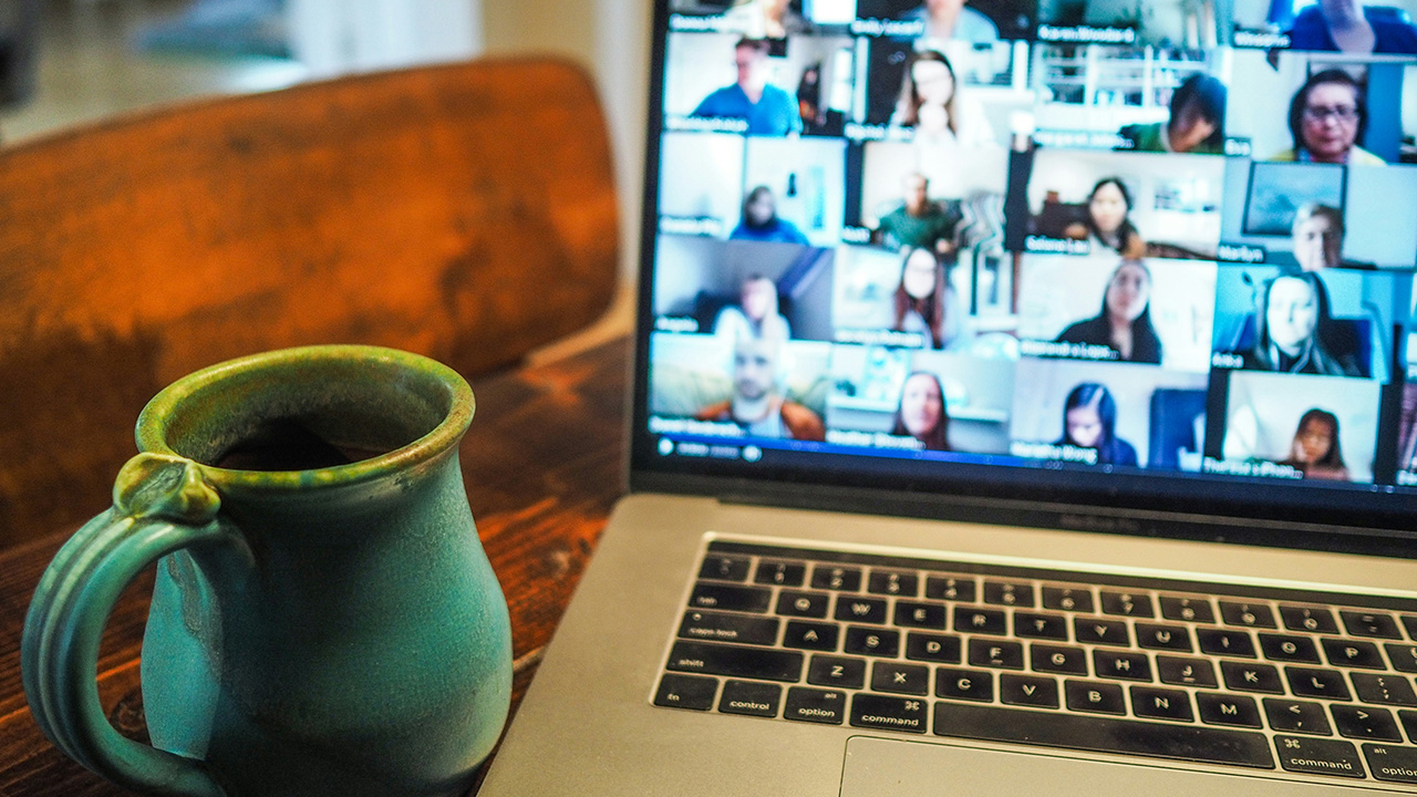 A coffee mug in front of a laptop screen